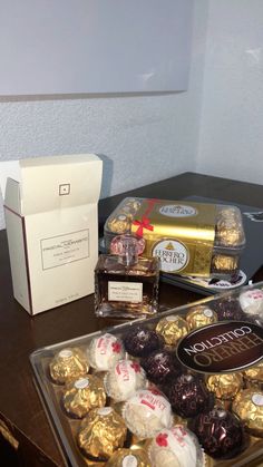 chocolates and candy are sitting on a table next to a box of gold foil