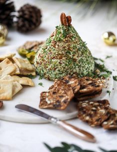 a plate topped with crackers and cookies next to a christmas tree shaped cone covered in sprinkles