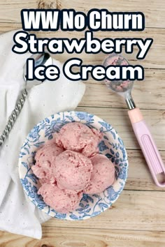 strawberry ice cream in a blue and white bowl on a wooden table with spoons