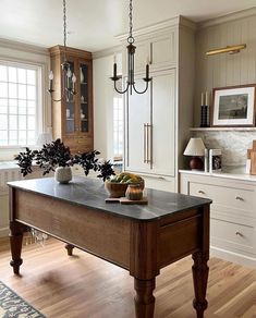 a large kitchen island in the middle of a room with white cabinets and wood floors