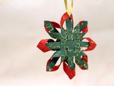 a green and red ornament hanging from a yellow string on a white background