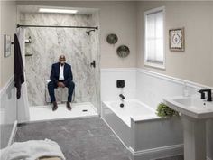 a man sitting on a toilet in a bathroom next to a sink and bathtub