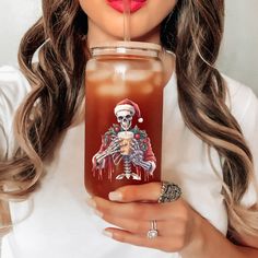 a woman holding a drink in her hand with a straw sticking out of it's mouth