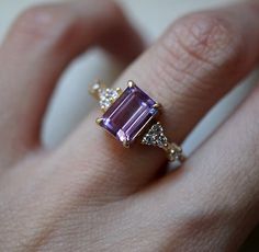 a woman's hand holding an amethorate and diamond ring