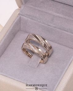 two wedding rings in a box with the lid open and diamond set on each side