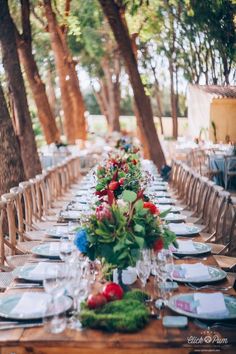 a long table with plates and place settings on it is set for an outdoor dinner