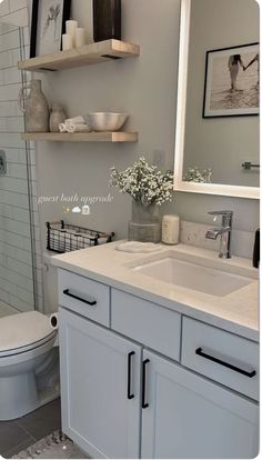 a bathroom with a sink, toilet and shower stall in the background is a white tiled wall