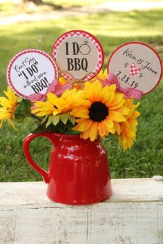 sunflowers in a red pitcher with labels on them for bbq party favors