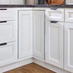 a kitchen with white cabinets and wooden cutting board