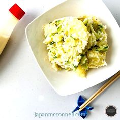 a white bowl filled with food next to chopsticks on top of a table