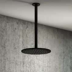 a shower head hanging from the ceiling in a room with concrete walls and flooring