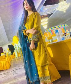 a woman standing in front of a table with yellow and blue cloths on it