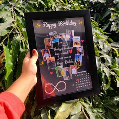 a person holding up a framed birthday card