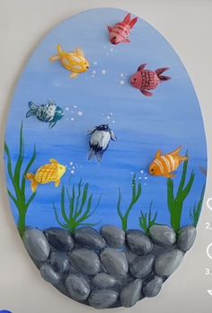 an oval painting with fish and rocks on it