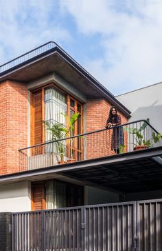 a person standing on the balcony of a brick building with plants growing out of their balconies