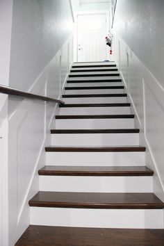 there is a set of stairs leading up to the second floor with white walls and wood floors