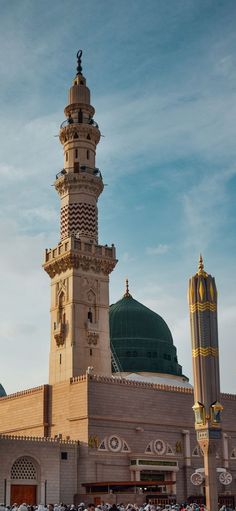 a large building with a green dome on top and many people standing around in front