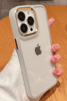 a woman's hand holding an iphone case on top of a wooden table next to a white towel