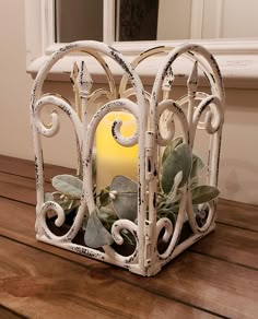 a candle is sitting in a white metal holder on a wooden table next to a mirror