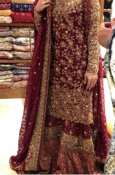 a woman in a maroon and gold outfit standing next to a pile of clothes at a store