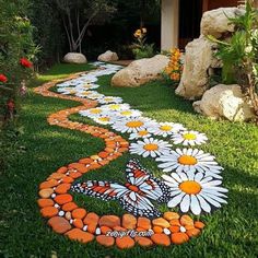 a pathway made out of rocks and stones with flowers painted on the grass in front of it