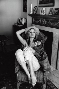 black and white photograph of a woman sitting on a chair in front of a fireplace