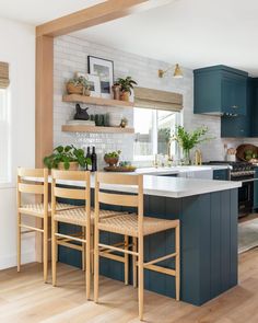 a kitchen with blue cabinets and white counter tops, wooden flooring and open shelving