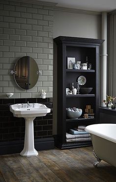 a white sink sitting next to a bath tub in a bathroom under a mirror on the wall