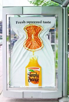 an advertisement for orange juice on the side of a bus stop