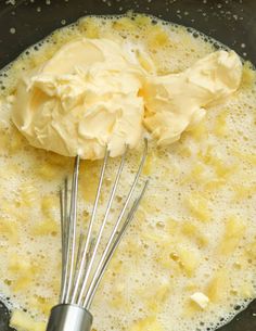 a whisk is being stirred in a pan with liquid and pineapple chunks