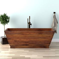 a wooden bathtub sitting on top of a hard wood floor next to a potted plant