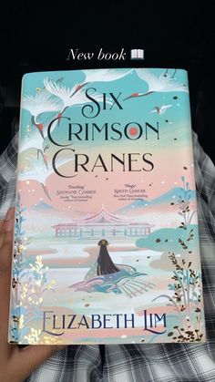 the cover of six crimson cranes by elizabeth jm is held up in front of a person's face