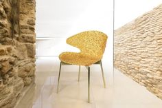 a yellow chair sitting in front of a stone wall next to a brick wall and floor