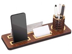 a cell phone and pen holder on a wooden stand with pens, pencils, and paper