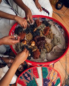 several people sitting around a red bowl filled with food