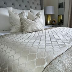 a bed with white and gold pillows on top of it