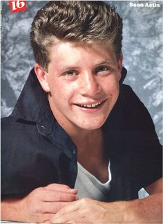 a young man is smiling and posing for a photo with his hand on his chest