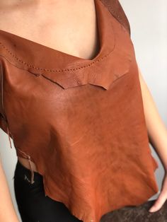 a woman is wearing a brown leather top