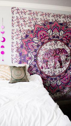 an elephant tapestry is hanging on the wall above a bed with pillows and throw pillows