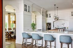 a kitchen with four stools in front of an island