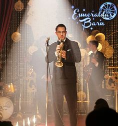 a man in a tuxedo holding a saxophone while standing next to a microphone