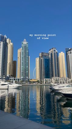 the city skyline is reflected in the water with boats parked on the shore and skyscrapers behind it