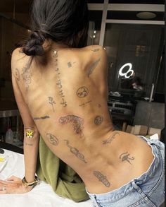 a woman with tattoos on her back sitting at a table