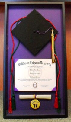 a graduation cap and tassel in a shadow box with a certificate attached to it