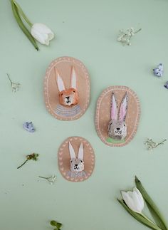 two paper bunnies with rabbits on them sitting next to flowers and tulips