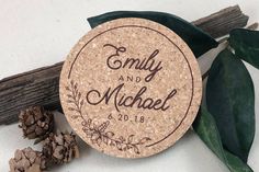 personalized cork coasters with the names and date printed on them next to pine cones