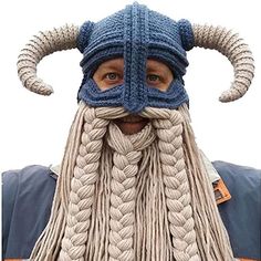 a man wearing a viking hat with long braids on his face and horns attached to it