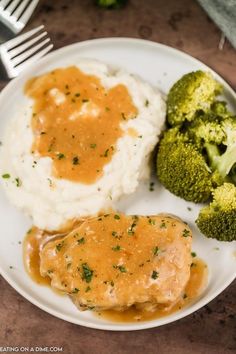 a plate with mashed potatoes, broccoli and gravy on it