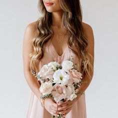 a woman in a pink dress holding a bouquet of white and pink flowers on her wedding day