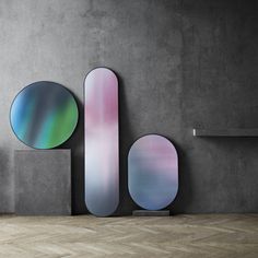 three skateboards are displayed on the wall in front of two different shapes and sizes